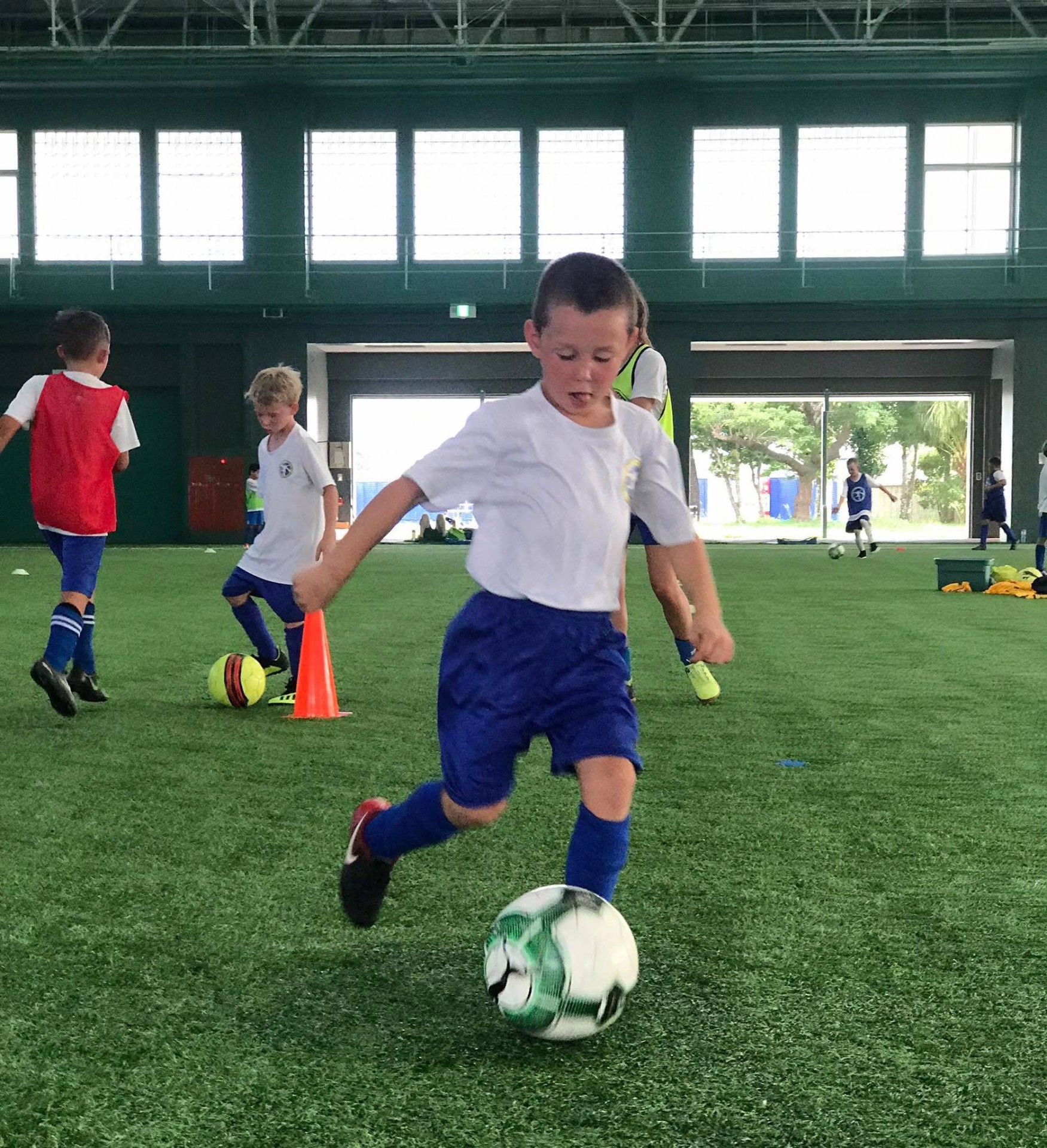 BSC Summer Camp 2019 — camper dribbling a ball on the indoor field